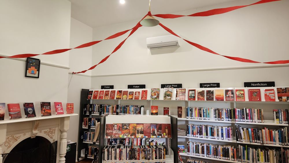 Library with books with red covers and red ribbons on the ceiling