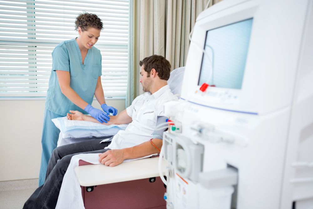 Man receiving an infusion in a day care centre helped by a nurse